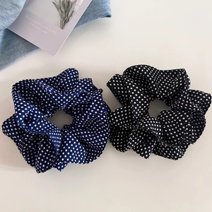 Detail view of navy and black polka dot scrunchies made of soft chiffon fabric