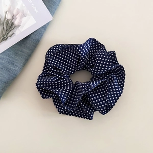 Detail of navy blue polka dot scrunchie with soft fabric folds and tulip card decoration