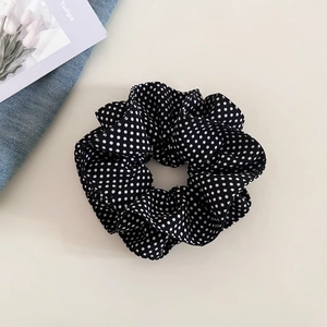 Detailed view of a navy blue polka dot scrunchie with satin texture and elastic band