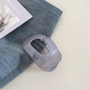 Détail de la pince à cheveux lilas translucide avec texture marbrée sur tissu denim