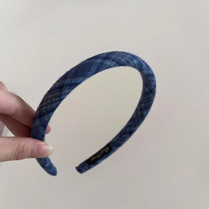 Detailed close-up of navy plaid fabric headband with inner logo label and soft texture
