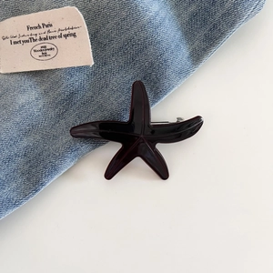 Detail view of the secure silver metal clip and dark red acetate starfish hair accessory