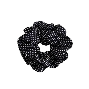 Classic navy blue polka dot scrunchie with soft pleated cotton fabric on white background