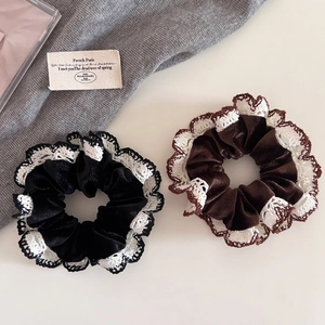 Close-up of elegant black and coffee velvet hair scrunchies with white lace edges