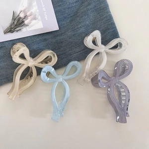 Detail of four colorful acetate ribbon bow hair claws in beige, blue, white, and purple