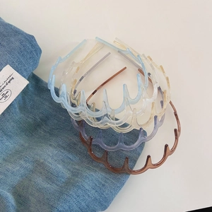 Detail of four transparent wavy hairbands in blue, amber, purple and brown resin