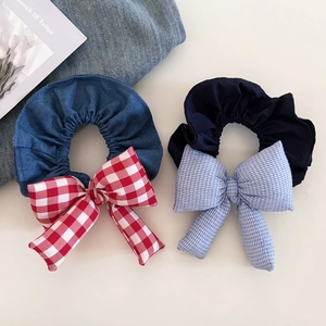 Close-up of denim fabric scrunchies with red and blue plaid bow details and soft texture