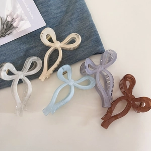 Flat lay of five acetate hair claw clips in pastel colors with a sleek bow design