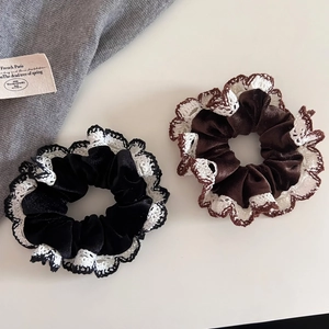 Detailed shot of black and brown velvet hair scrunchies with white crochet lace edges