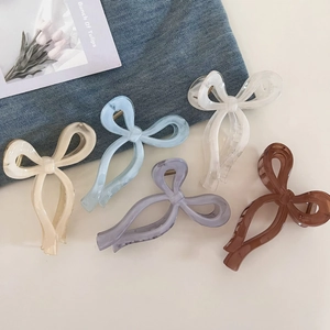 Detail showing five marbled acetate bow hair claws in various colors on a soft background