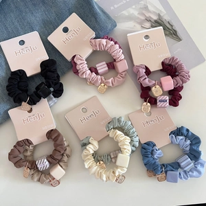 Set of minimalist colorful scrunchies with square beads and gold metal charms on denim