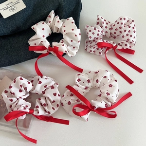 Detail view of four floral and polka dot fabric scrunchies with red silk ribbon bows