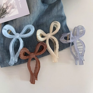 Detail of four colorful bow hair claws in blue, cream, brown, and purple hues