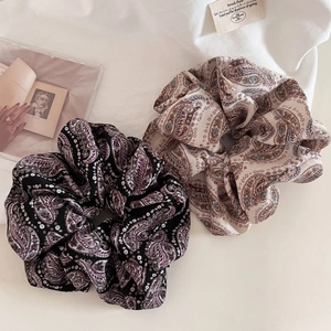 Detailed shot of paisley print scrunchies in black and beige on soft fabric background