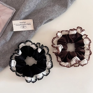 Detailed view of black and brown velvet scrunchies with elegant white lace borders