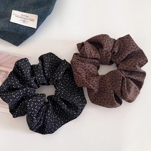 Detailed view of leopard print and floral scrunchies with soft pleated fabric texture