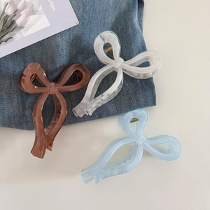 Close-up of blue and marble white acrylic bow hair claws with durable golden metal springs