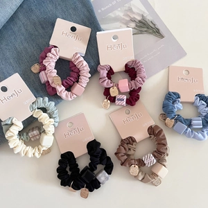 Detail of high-elastic scrunchies with square beads and gold charms on card