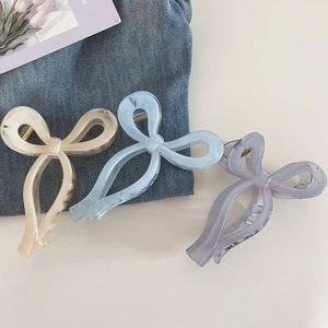 Close-up of three colorful bow hair claws featuring marble texture and ribbon style shapes