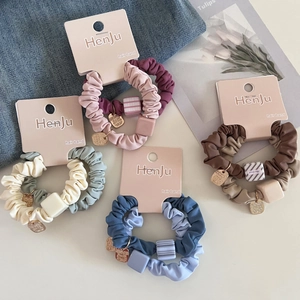 Detail of colorful scrunchie set with square charms and gold pendants on brand cards
