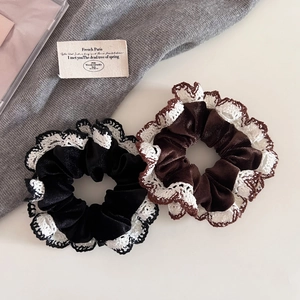 Detail view of two velvet hair scrunchies with white lace trim in black and dark brown