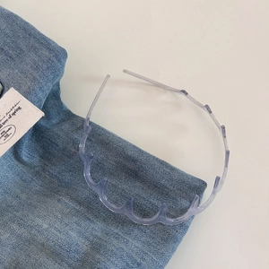 Close-up of transparent wavy plastic headband with teeth on blue denim fabric background
