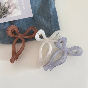 Detailed view of translucent resin bow hair claws in amber, pearl white, and purple