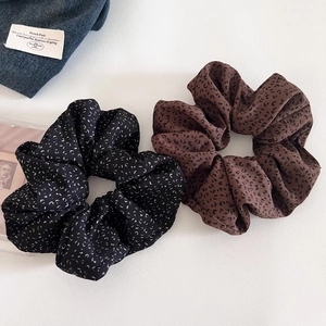 Close-up of leopard print scrunchies in black and brown fabric on white background