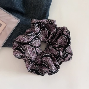Close-up of purple paisley hair scrunchie on blue denim background for retro hairstyles