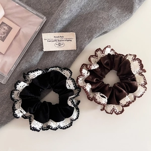 Close-up of velvet scrunchies with white lace edges in black and dark brown colors
