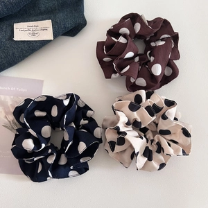 Three vintage polka dot scrunchies in coffee, navy, and cream for stylish bun hairstyles