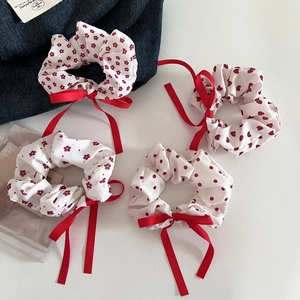 Detail view of four red floral and polka dot hair scrunchies with elegant ribbon bows