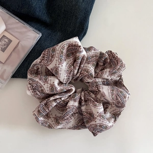 Macro detail of beige paisley pattern scrunchie with soft pleated chiffon fabric texture