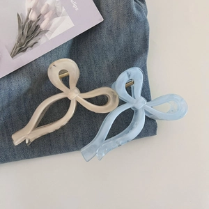 Detail view of light blue and cream bow hair claws with marble acetate texture on denim