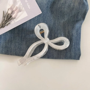 Close-up of a white marble texture resin bow hair claw clip on denim background