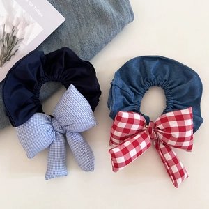 Close-up of navy and denim blue bow hair scrunchies with plaid patterns on a beige surface