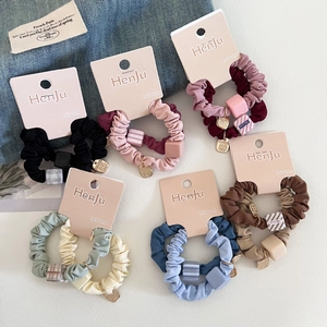 Detail of 12-piece colorful scrunchie set with geometric charms on display card