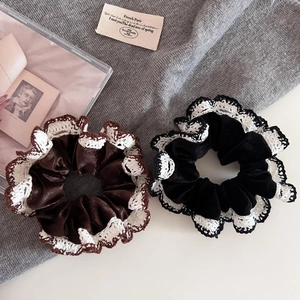 Close-up of black and brown velvet scrunchies with white lace edges in French retro style