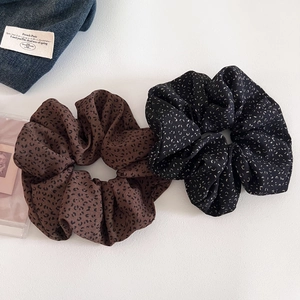 Detailed view of two oversized leopard print and dotted scrunchies on white background