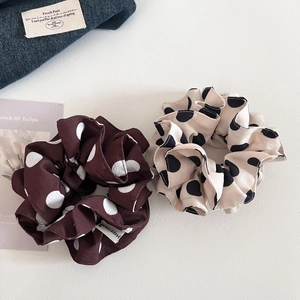 Close-up of vintage brown and beige polka dot oversized hair scrunchies on white surface