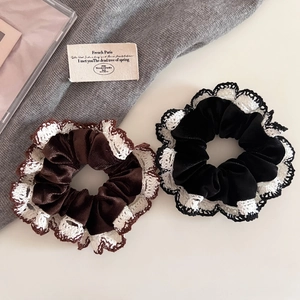 Close-up of velvet scrunchies in black and brown with delicate white lace crochet edges