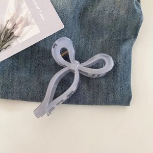 Close-up of a translucent light purple bow hair claw clip on denim background