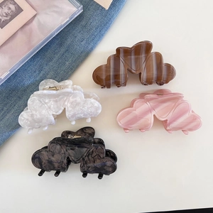 French style acetate heart hair claw clips in four colors on a denim background