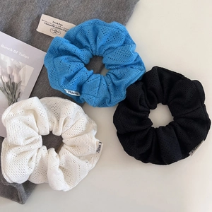 Vue détaillée des chouchous en tricot bleu, noir et blanc avec un tissu à mailles ajourées
