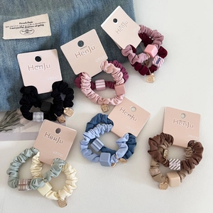 Close-up of colorful scrunchies with square beads and gold metal charms on card