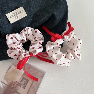 Detail showing two white scrunchies with red heart and polka dot prints plus silk ribbons