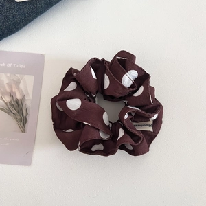Detail showing dark brown polka dot scrunchie with happiness fabric tag and soft texture