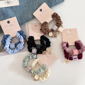 Detailed view of five Morandi colored fabric hair scrunchies with square matte ornaments