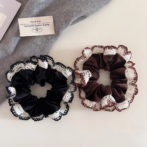 Detail view of retro velvet scrunchies with white lace edges in black and brown