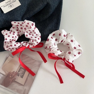 Detail of red floral scrunchies with satin bow ribbons on a textured surface